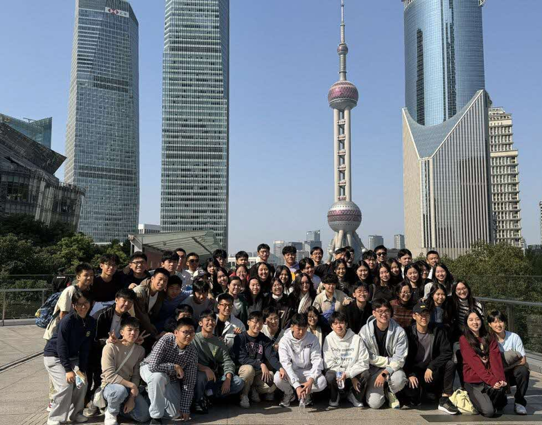 Immersion Trip A large group of students posing in front of Shanghai's iconic skyline featuring the Oriental Pearl Tower.